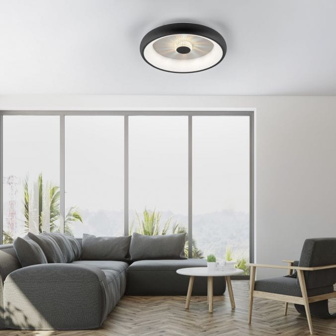 Plafon LED Vertigo 29W CCT w kolorze czarnym, okrągły, zamontowany na suficie. Wyposażony w pilot do zdalnego sterowania. Tło przedstawia nowoczesny salon z dużymi oknami i meblami w odcieniach szarości.