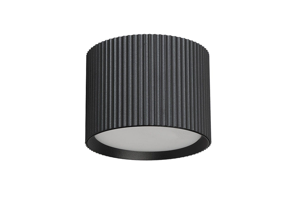 Lampa sufitowa Gisele w kształcie tuby, czarna, z rowkowaną fakturą. Wyposażona w oprawę GX53, montowana na suficie. Widoczny okrągły klosz z mlecznego materiału u dołu. Produkt prezentowany w frontalnym ujęciu na jednolitym tle.
