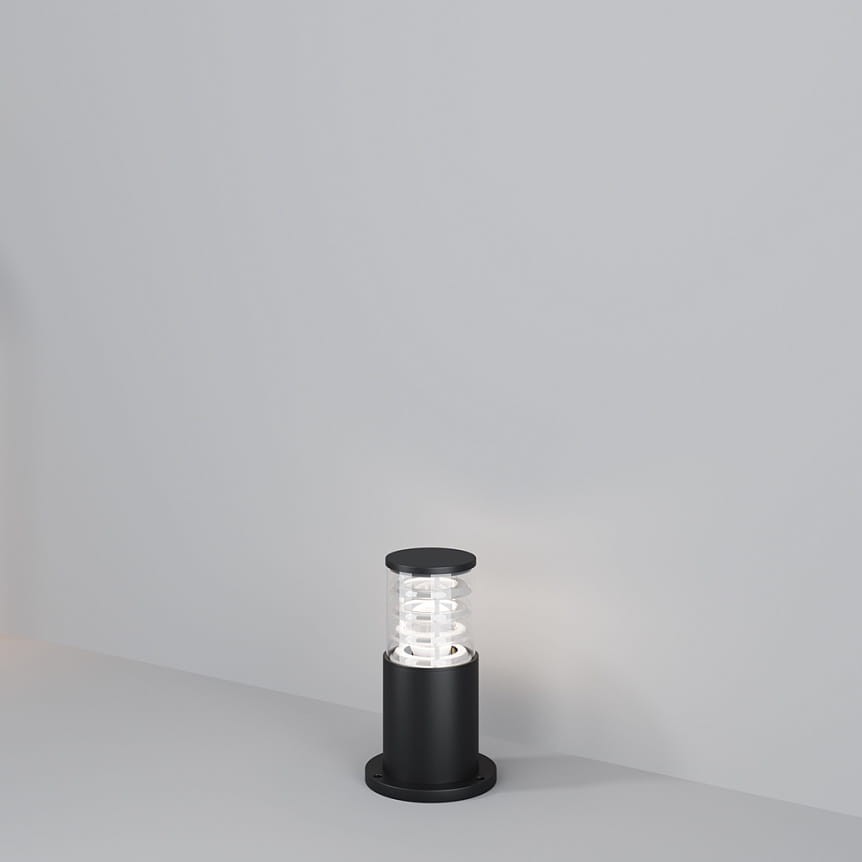 Lampa ogrodowa Bronx H25 w kolorze czarnym, z oprawą na żarówkę E27. Okrągła podstawa, przezroczysta osłona z falistym wzorem, stojąca na płaskiej powierzchni. Prosta forma, idealna do oświetlenia przestrzeni zewnętrznych.