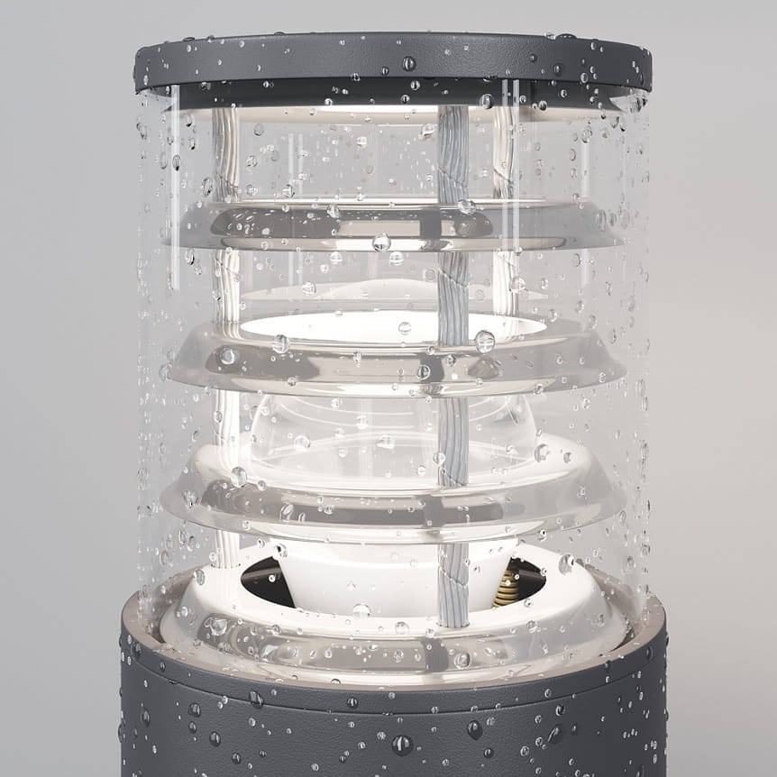 Grafitowa lampa ogrodowa Bronx H25 z jednym gniazdem E27, z przezroczystym kloszem z tworzywa, z widocznymi okrągłymi elementami wewnętrznymi, umieszczona w wodoodpornej obudowie, ujęcie z boku z kroplami wody na powierzchni.