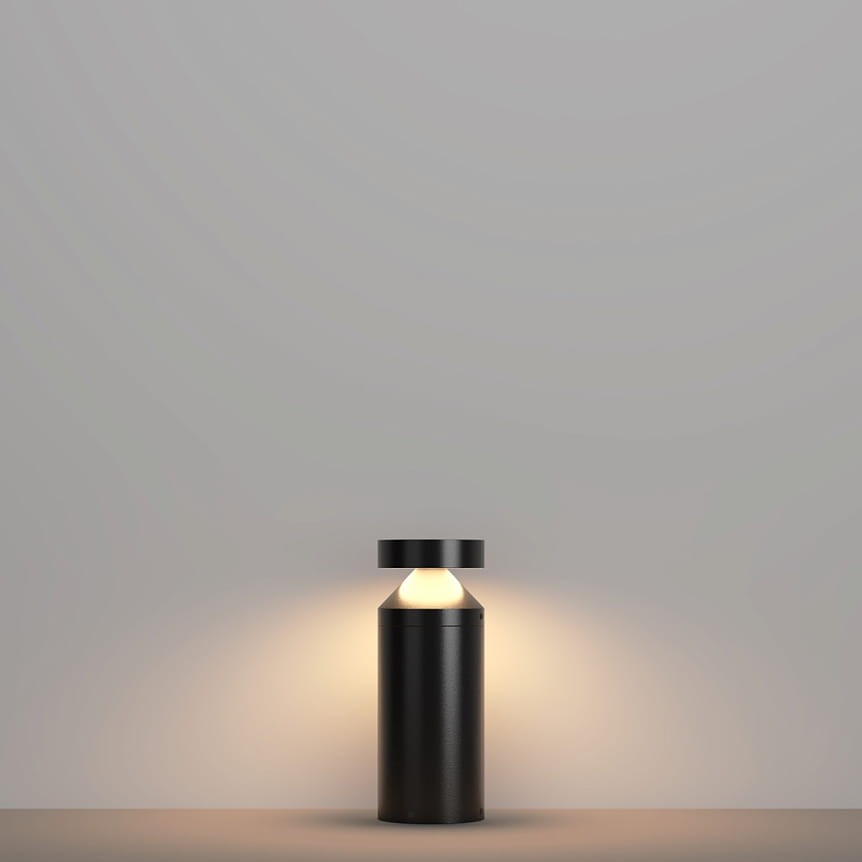 Lampa ogrodowa Olten H30 LED 12W 3000K w kolorze grafitowym. Stojąca, cylindryczna konstrukcja z okrągłym kloszem u góry, emitująca ciepłe światło. Tło proste, jednolite, co podkreśla minimalistyczny design lampy.
