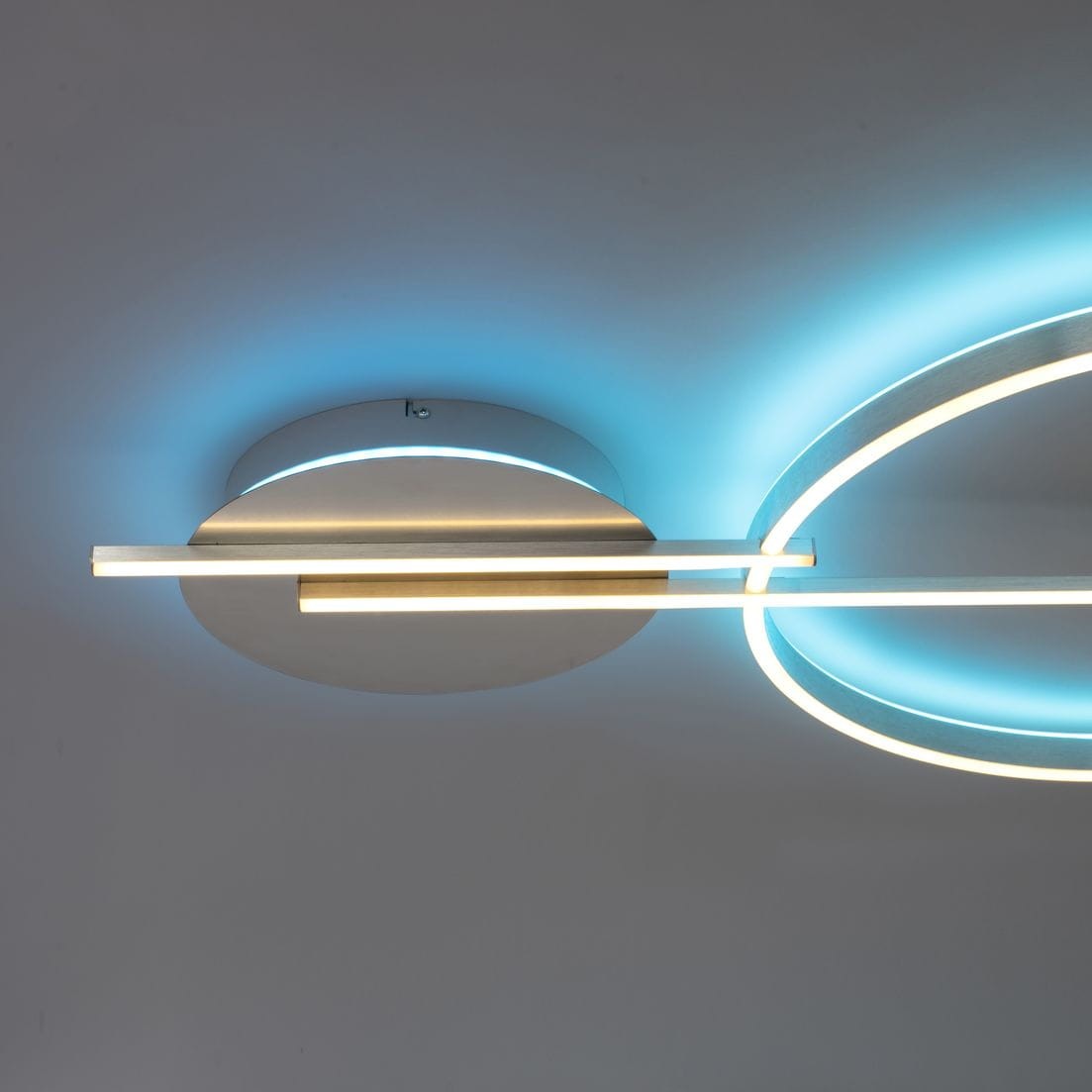 Lampa sufitowa Q-arkoa w kolorze srebrnym, z pilotem, z dwoma źródłami światła LED 36W. Posiada okrągłą podstawę oraz dwa prostokątne elementy świetlne. Efektowne podświetlenie w odcieniu niebieskim. Zamontowana na suficie.