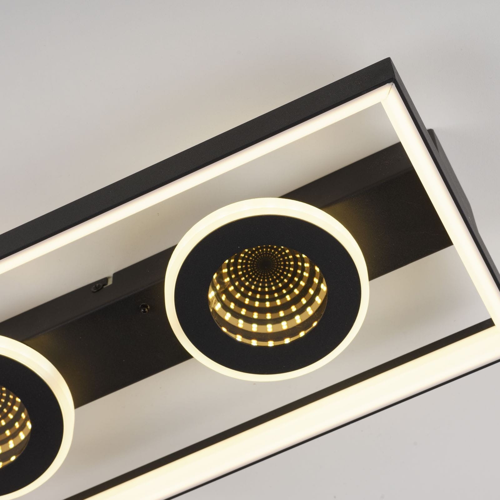 Lampa sufitowa Traforo LED 20W CCT w kolorze czarnym z pilotem. Posiada trzy okrągłe klosze z diodami LED, otoczone białym pierścieniem. Ujęcie z góry, pokazujące detale kloszy i ich teksturę.