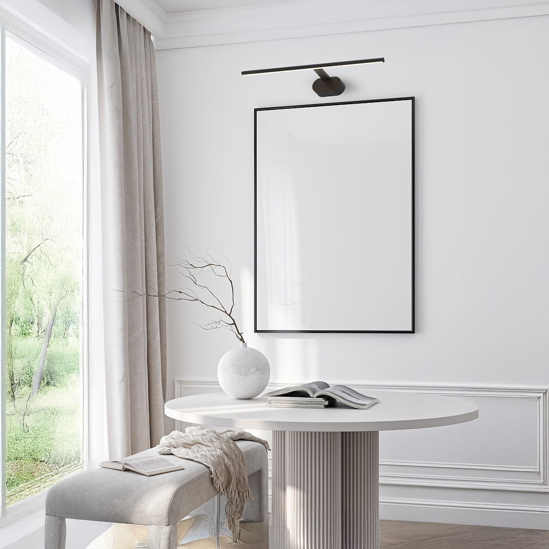 Kinkiet Prado L60 LED 11W 3000K w kolorze czarnym, zamontowany na ścianie nad pustą ramą w białej przestrzeni. Prosty, minimalistyczny design z prostokątnym źródłem światła, idealny do nowoczesnych wnętrz.
