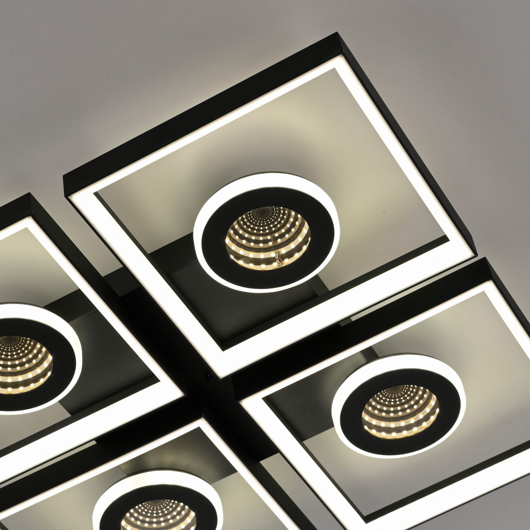 Lampa sufitowa Traforo LED 35W CCT w kolorze czarnym, z czterema okrągłymi reflektorami otoczonymi białym podświetleniem, montowana na suficie, widok z dołu.