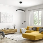 Czarna lampa wisząca LED Lorenzo 35W 4000K, o nowoczesnym, okrągłym kształcie, zawieszona na cienkim metalowym przewodzie. Produkt znajduje się w jasnym wnętrzu z żółtą sofą, drewnianym stolikiem i dużym oknem.