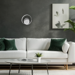 Kinkiet LED Lucero 13W 4000K w chromowanej obudowie, zamontowany na ciemnej ścianie. W tle widoczna biała sofa z zielonymi poduszkami oraz stół z rośliną doniczkową i książką.
