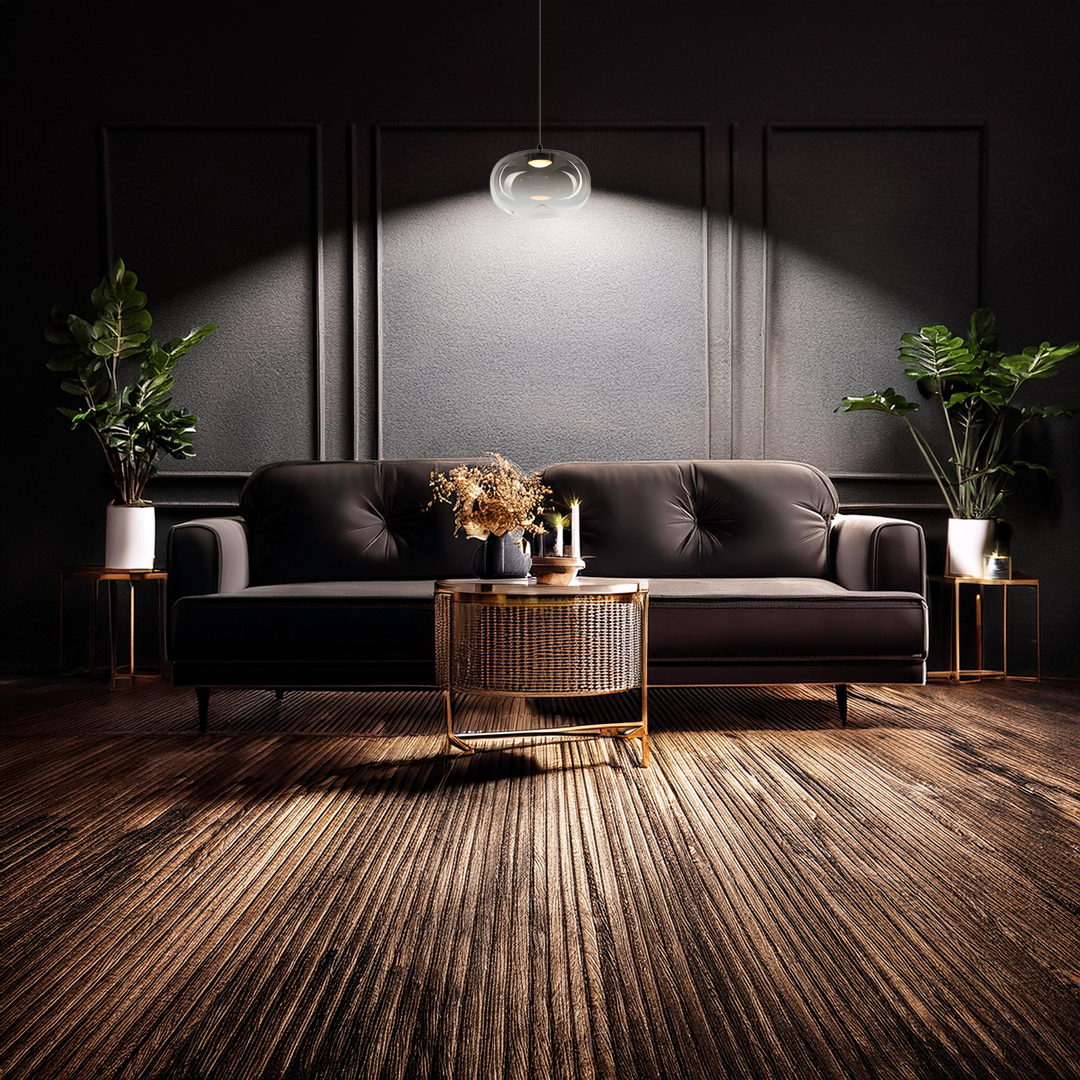 Lampa wisząca LED Vaso 1 l 4W 3000K w kolorze czarnym z dymionym kloszem, zawieszona nad czarną sofą. W tle ciemne ściany oraz rośliny w doniczkach, stół z plecionki z dekoracjami. Oświetlenie tworzy przytulną atmosferę.