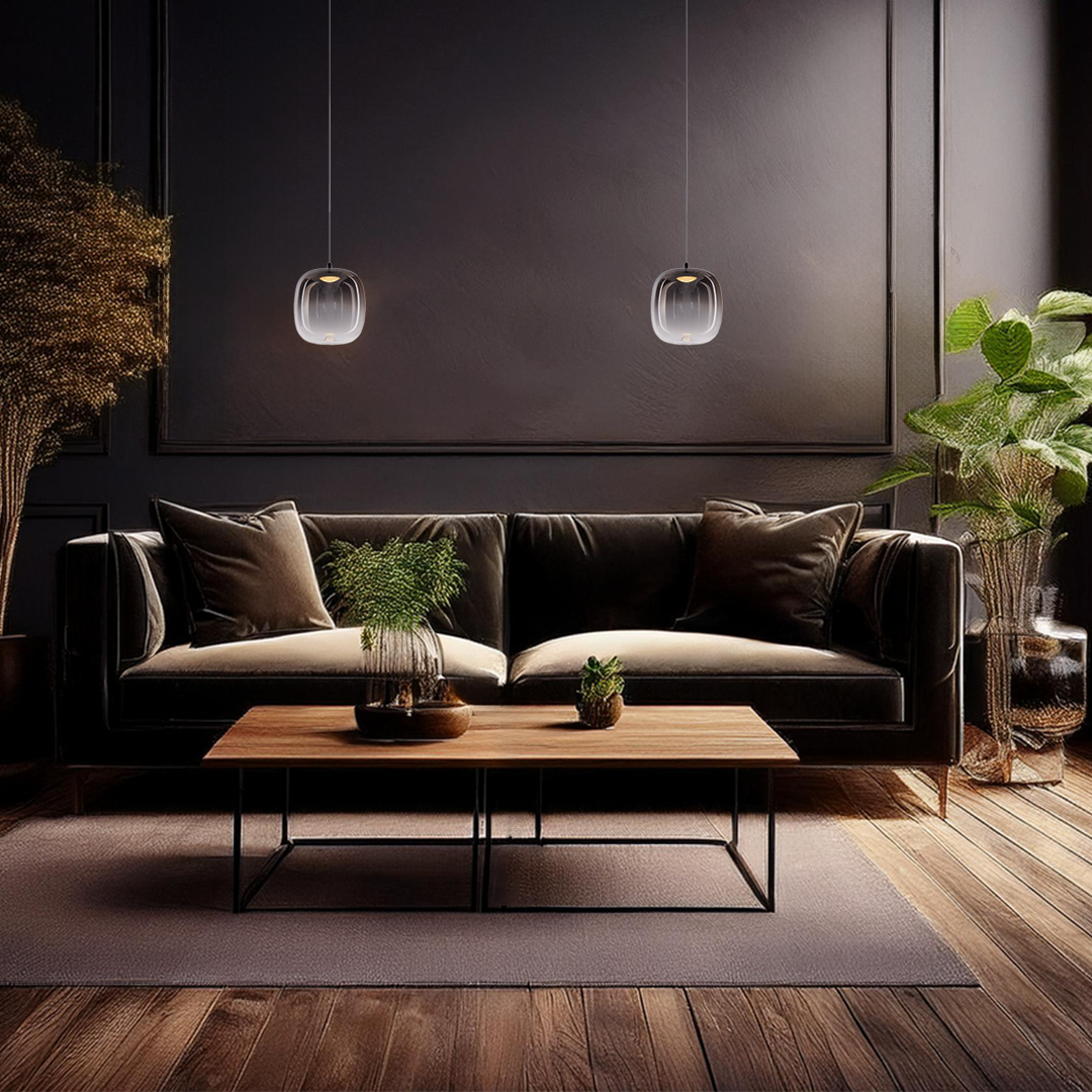 Lampa wisząca LED Vaso 2 l z czarnym, dymionym kloszem, zawieszona nad drewnianym stolikiem w nowoczesnym wnętrzu. W tle skórzana sofa i rośliny w dekoracyjnych doniczkach, na ciemnym tle ściany.