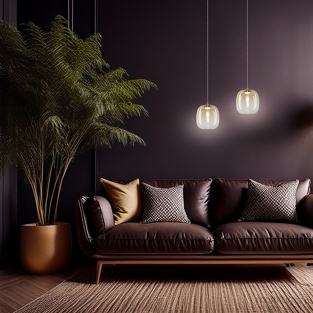 Lampa wisząca LED Vaso 2 l, 4W, 3000K w kolorze złotym i bursztynowym, zawieszona na cienkich linkach, w nowoczesnym wnętrzu z ciemną ścianą, obok brązowej sofy z poduszkami. W tle widoczna roślina doniczkowa.