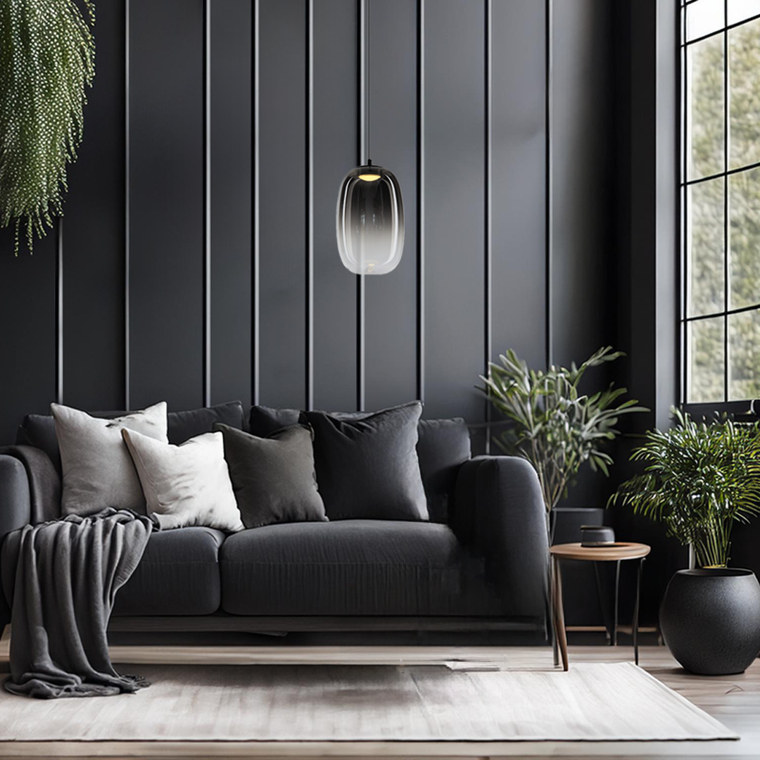 Lampa wisząca LED Vaso 3 l, 4W, 3000K, w kolorze czarnym z dymionym kloszem, zawieszona nad ciemnoszarym sofą z poduszkami. W tle czarne panele ścienne i okno z widokiem na zieleń.
