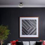 Lampa sufitowa LED Vaso 4W 3000K w kolorze czarnym z dymionym kloszem, zamontowana na suficie. W tle widoczna ciemna ściana oraz abstrakcyjny obraz w ramie, obok kanapa z poduszkami w kolorze czerwonym i białym.