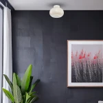 Lampa sufitowa LED Vaso 4W 3000K w białym kolorze, okrągła, zamontowana na suficie w nowoczesnym wnętrzu. W tle ciemna ściana oraz obraz w ramie, obok roślina doniczkowa.