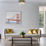 Lampa sufitowa LED Vaso 12W 3000K w kolorze złotym i bursztynowym, z okrągłym, metalowym kloszem. Zawieszona na suficie, w nowoczesnym wnętrzu z białą sofą i złotymi poduszkami. Obraz w tle przedstawia most Golden Gate.