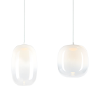 Lampa wisząca LED Vaso 15W 3000K w białym kolorze, z przezroczystym kloszem o zaokrąglonym kształcie, zawieszona na cienkim przewodzie. Widać dwa różne modele lampy, jeden bardziej prostokątny, a drugi o lekko okrągłym kształcie.
