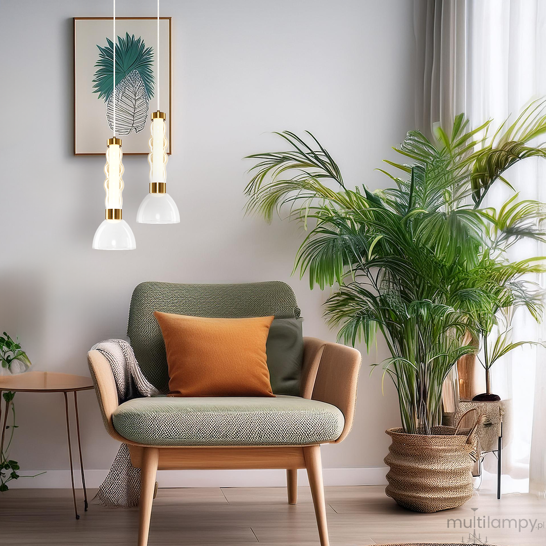 Lampa wisząca LED Lucco 13W 3000K w kolorze złotym i bursztynowym, z białymi kloszami, zawieszona nad zieloną roślinnością, w aranżacji z fotelem i stolikiem. Oświetlenie w nowoczesnym wnętrzu.