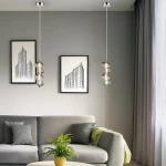Lampa wisząca LED Bolla 17W 3000K w chromowanej oprawie z dymionymi kloszami, zawieszona na cienkim kablu. W tle widoczna szaro-beżowa ściana, kanapa z poduszkami i roślina doniczkowa.