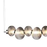 Lampa wisząca LED Bolla 32W 3000K w kolorze chromu z dymionymi kloszami. Składa się z sześciu okrągłych, żłobkowanych kloszy, zawieszonych na cienkim przewodzie. Klosze emitują ciepłe światło, tworząc efektowną atmosferę.