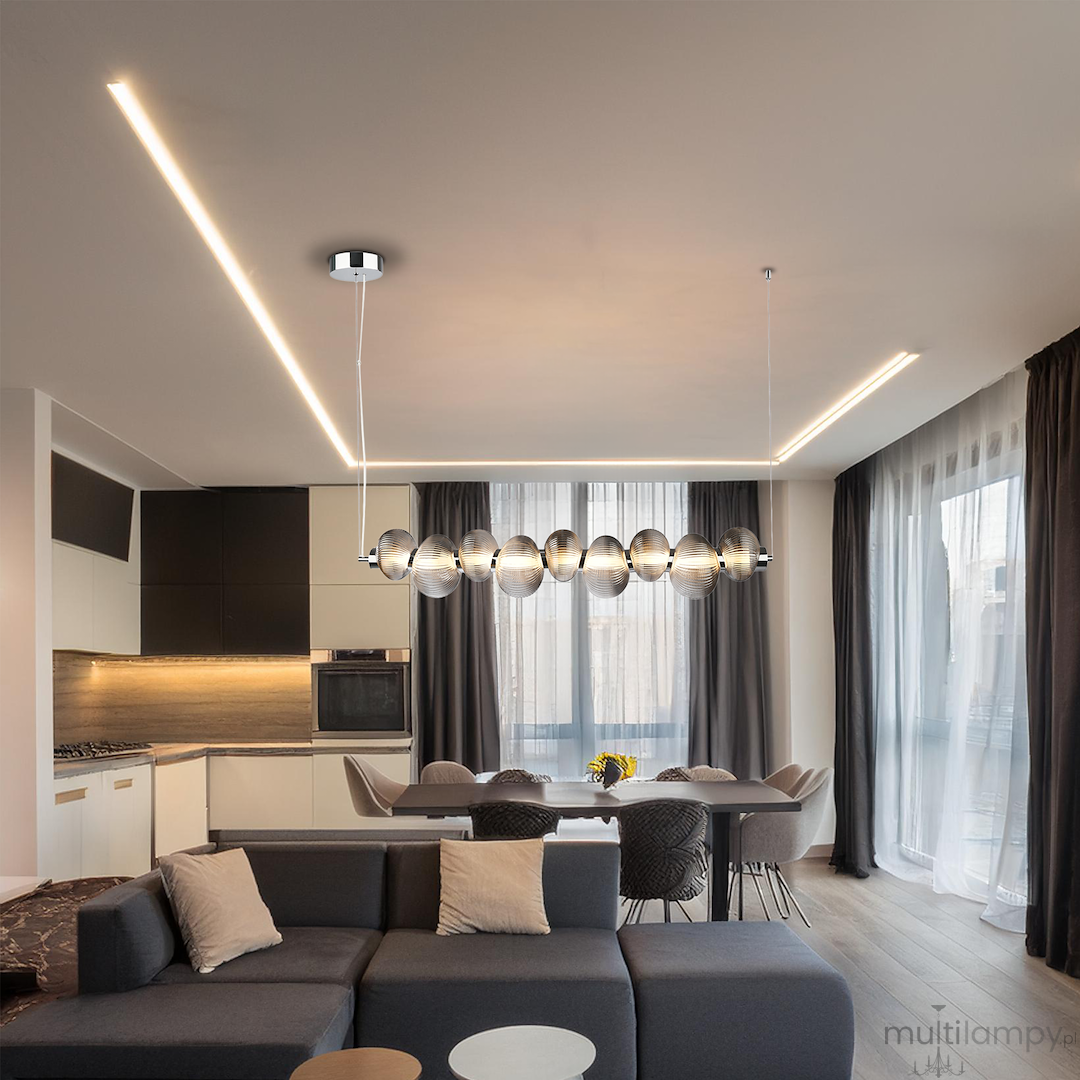 Lampa wisząca LED Bolla 32W 3000K w chromie z dymionym kloszem, zwisająca w nowoczesnym wnętrzu. Klosze mają okrągły kształt, a w tle widać elegancką aranżację kuchni z jadalnią, z jasnymi zasłonami i szarym narożnikiem.