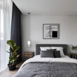 Lampa wisząca LED Arame 15W 3000K w kolorze czarnym, zawieszona nad łóżkiem w nowoczesnej sypialni. Okrągła metalowa podstawa z siatką, szkło w kształcie tuby. W tle roślina doniczkowa, szare zasłony i minimalistyczne dekoracje.