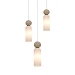 Lampa wisząca Santos z trzema źródłami światła G9, z białymi szklanymi kloszami w kształcie cylindrów, zawieszona na cienkich przewodach. Elementy dekoracyjne w kolorze mosiądzu oraz okrągłe, kamienne podstawy. Tło proste, białe.