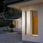 Lara 150 kinkiet elewacyjny LED 45W 4000K w kolorze czarnym, prostokątny, zamontowany na ścianie budynku. Emituje jasne światło, oświetlając elewację. Widoczny w kontekście zewnętrznym, obok okna i zieleni.