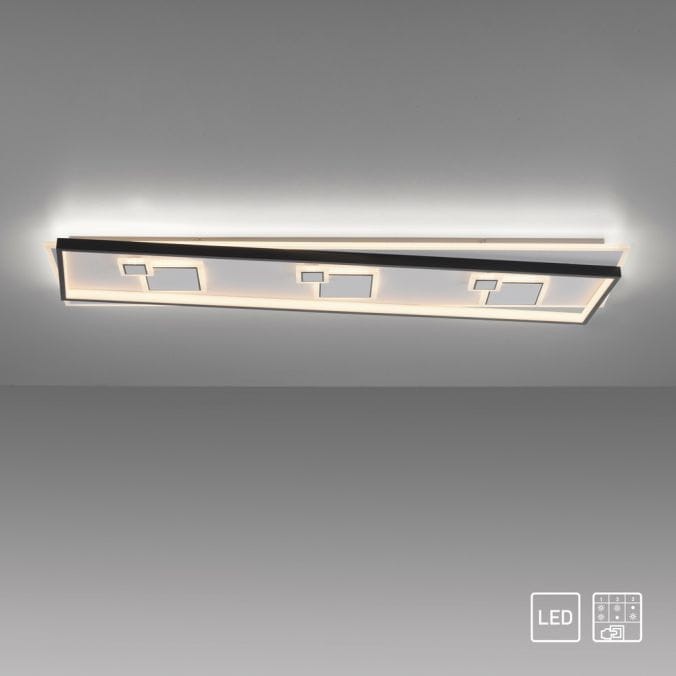 Mailak XL lampa sufitowa LED 39W 3000K w kolorze czarnym, o prostokątnym kształcie, z dekoracyjnymi wycięciami. Zamontowana na suficie, emituje ciepłe światło, delikatnie oświetlając otoczenie. Tło jasne, minimalistyczne.