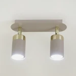 Lampa sufitowa Joker z dwoma spotami w kolorze kaszmiru i złota, montowana na prostokątnej podstawie. Lampy mają cylindryczny kształt, z jasnym światłem emitowanym przez żarówki GU10.