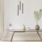 Lampa wisząca Joker 3xGU10 w kolorze kaszmiru z złotymi detalami. Trzy cylindryczne klosze zawieszone na cienkich linkach, w aranżacji na tle jasnej ściany, nad nowoczesnym stołem z dekoracjami.