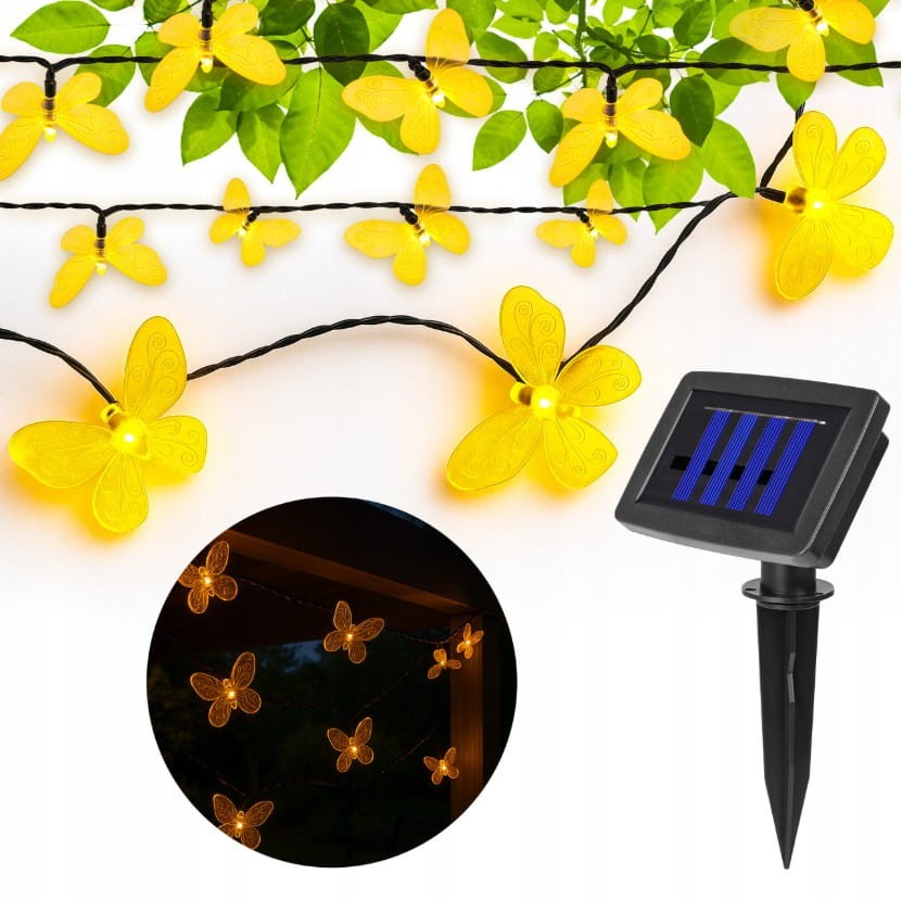 Girlanda solarna o długości 580 cm z 20 LED w kształcie żółtych motylków. Motylki umieszczone na czarnym przewodzie, z solarnym panelem w kształcie prostokąta. Elementy dekoracyjne idealne do ogrodu, na tle zielonych liści.