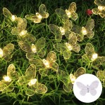 Girlanda solarna o długości 580 cm z 20 przezroczystymi motylkami LED, umieszczona na zielonej trawie. Motylki mają szczegółowe wzory i emitują ciepłe światło, tworząc dekoracyjną iluminację w ogrodzie.