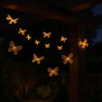 Girlanda solarna o długości 580 cm z 20 LED w kształcie motylków. Motylki w kolorze ciepłego żółtego światła, zawieszone na ciemnym przewodzie, tworzą efektowną dekorację ogrodową w nocy.