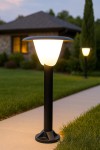 Lampa stojąca ogrodowa Bianca H66 w kolorze czarnym, z materiałowym kloszem w kształcie stożka. Ustawiona na chodniku, z widocznym podświetleniem. Klosz emituje ciepłe światło, a lampa ma prostą, cylindryczną podstawę.