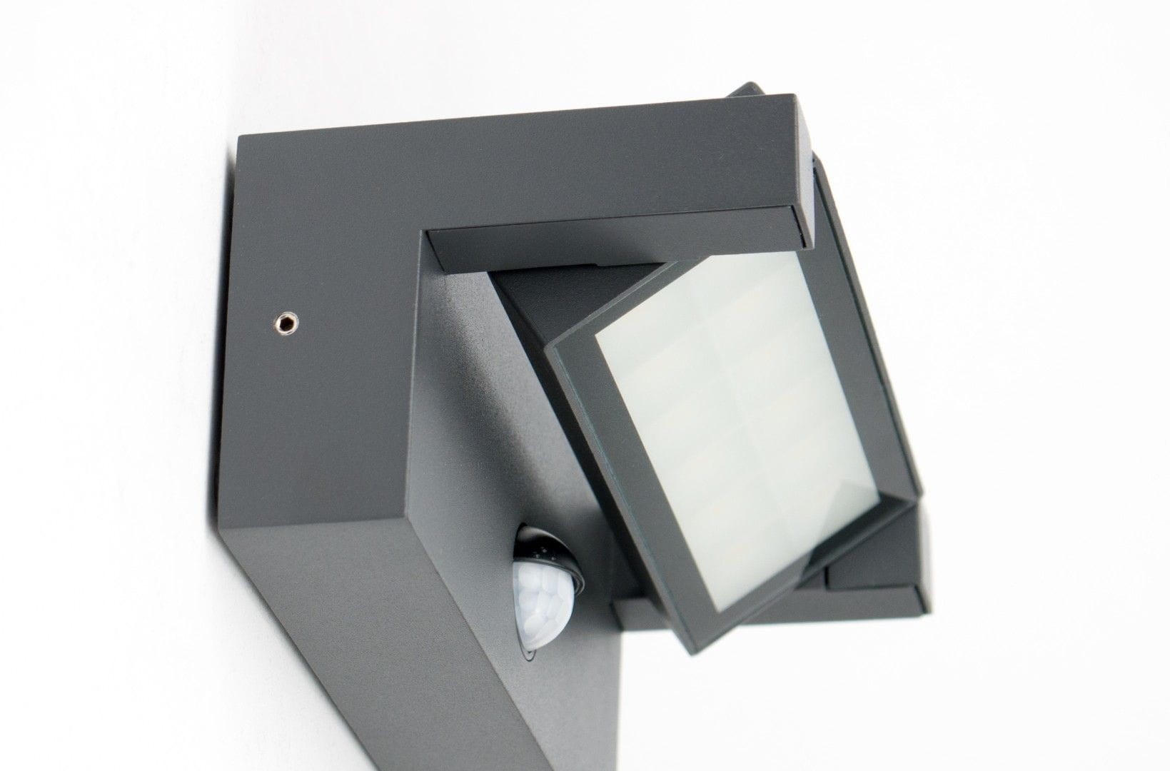 Kinkiet elewacyjny kierunkowy LED 21W w ciemnym popiele, z czujnikiem ruchu. Produkt zamontowany na ścianie, z widoczną szklanym kloszem i czujnikiem. Kąt ujęcia pokazuje detale konstrukcji oraz fakturę materiału.