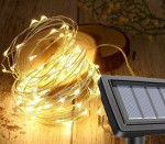 Girlanda świetlna ogrodowa solarna z 200 diodami LED, o długości 20 m. Złota, elastyczna żyłka z lampkami owinięta wokół drewnianego klocka. Widoczny panel solarny z przodu, który umożliwia ładowanie energią słoneczną.