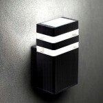 Kinkiet elewacyjny ogrodowy Inez w kolorze czarnym, 1-punktowy. Produkt ma prostokątny kształt, z przezroczystymi elementami pośrodku, montowany na ścianie. Widoczny na tle szarej, teksturowanej powierzchni.