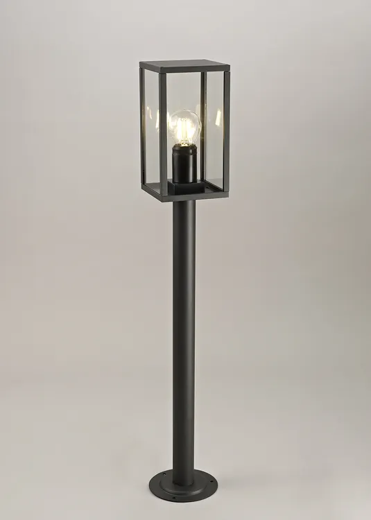 Lampa stojąca ogrodowa Malmo H68 w kolorze grafitowym, z kwadratową, przezroczystą obudową, umieszczona na prostym, cylindrycznym słupku. Widoczna żarówka wewnątrz, montaż na płaskiej podstawie. Ujęcie frontalne.