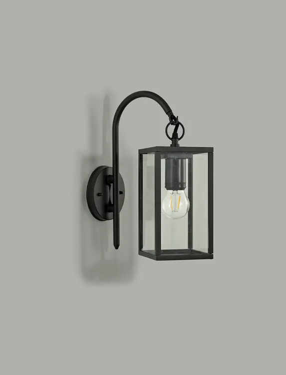 Malmo kinkiet elewacyjny ścienny 1-punktowy w kolorze grafitowym z metalową konstrukcją, prostokątnym kloszem z przezroczystego szkła, zawieszony na ścianie. Widoczna żarówka wewnątrz obudowy.