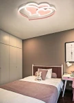 Lampa sufitowa w kształcie serc w kolorze różowym z funkcją LED 66W CCT, zamontowana na suficie. Oświetlenie w stylowej sypialni z jednolitym tłem, z widocznym łóżkiem i dekoracjami. Pilot do zdalnego sterowania w zestawie.
