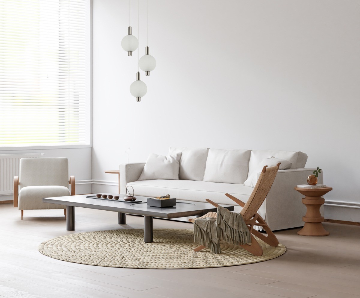 Lampa wisząca Lenti z trzema okrągłymi kloszami w kolorze białym i złotymi detalami. Klosze zawieszone na cienkich linkach, w nowoczesnym wnętrzu z jasnymi meblami i dywanem. Idealna do aranżacji salonu.