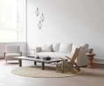 Lampa wisząca Lenti z trzema okrągłymi kloszami w kolorze białym i złotymi detalami. Klosze zawieszone na cienkich linkach, w nowoczesnym wnętrzu z jasnymi meblami i dywanem. Idealna do aranżacji salonu.