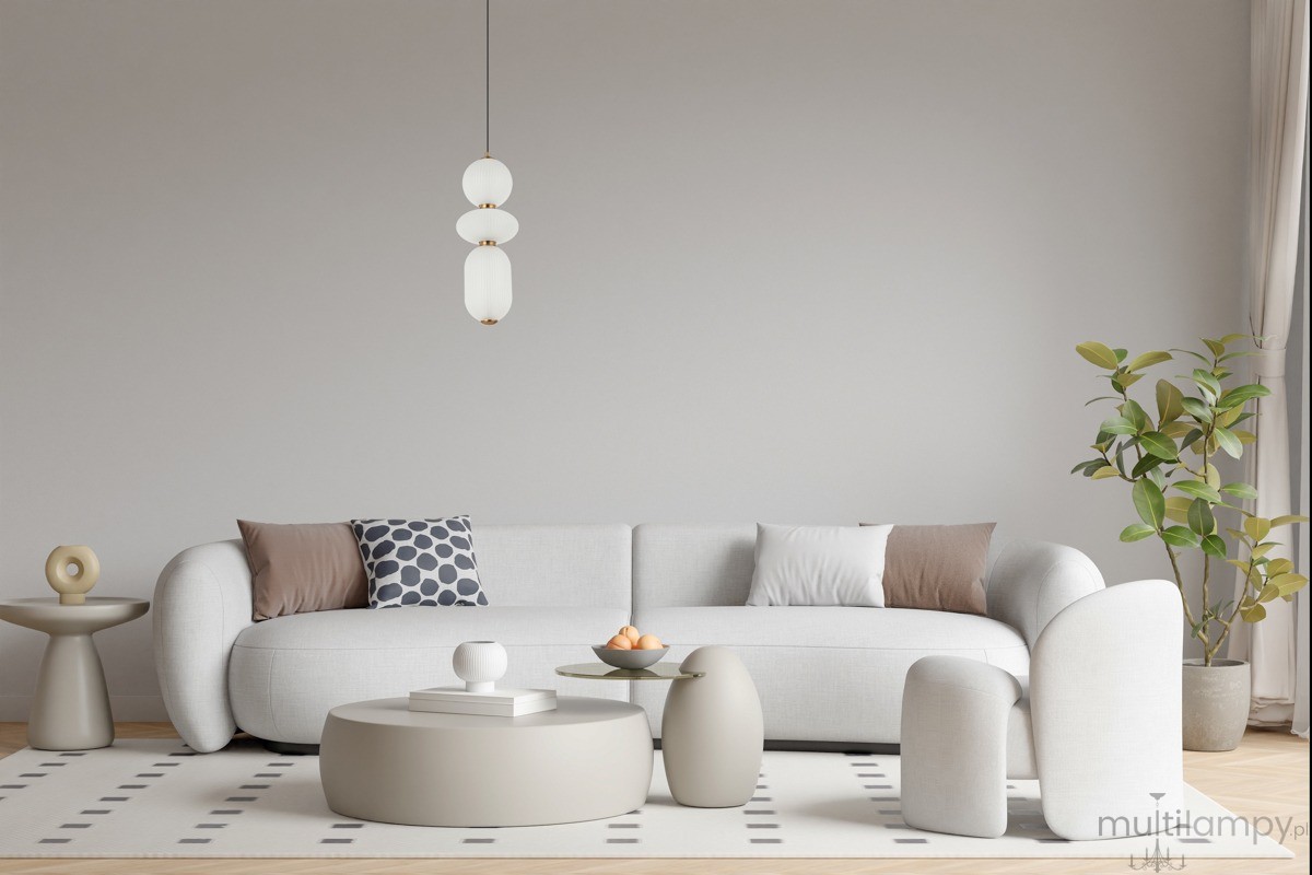 Lampa wisząca Nico 3xLED 15W w kolorze złotym i białym, zawieszona nad jasnoszarym sofą. Składa się z trzech okrągłych kloszy o gładkiej teksturze, z metalowymi detalami. Tło w neutralnym odcieniu, w aranżacji nowoczesnego wnętrza.