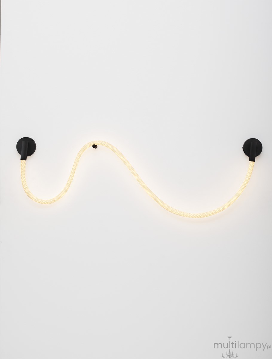 Cura kinkiet 1xLED 14W w kolorze czarnym z elastycznym, żółtym przewodem, zamontowany na białej ścianie. Kinkiet ma nowoczesny design, z dwoma czarnymi mocowaniami, tworzącym falisty kształt źródła światła.