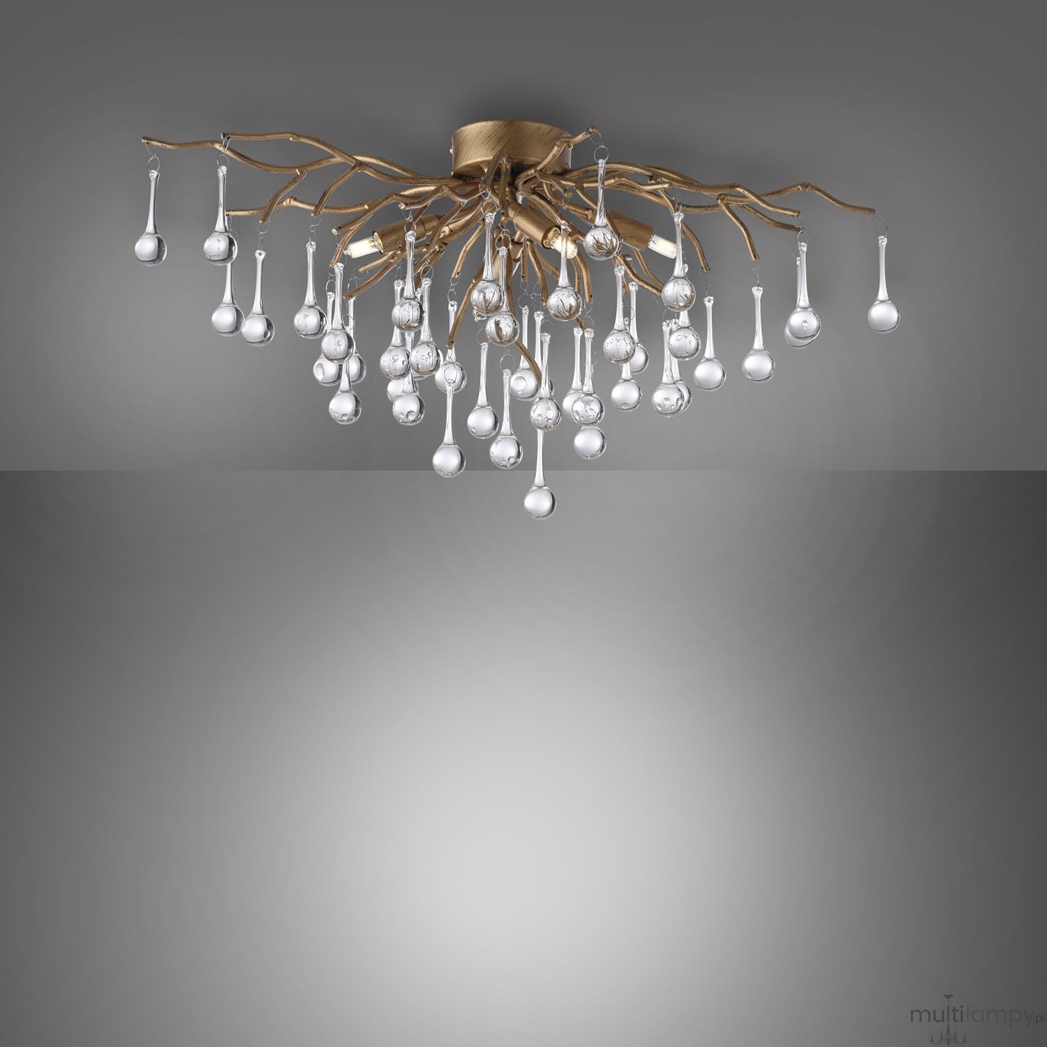 Lampa sufitowa Icicle w postarzanym mosiądzu z 4 gniazdami G9. Abstrakcyjny design z gałęziami i wiszącymi, przezroczystymi kroplami w różnych rozmiarach, tworząc elegancką kompozycję. Ujęcie z góry na tle szaro-białym.