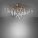 Lampa sufitowa Icicle w postarzanym mosiądzu z 4 gniazdami G9. Abstrakcyjny design z gałęziami i wiszącymi, przezroczystymi kroplami w różnych rozmiarach, tworząc elegancką kompozycję. Ujęcie z góry na tle szaro-białym.