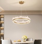 Lampa wisząca LED Montana 26W 3000K w złotym kolorze, okrągła, z przezroczystymi elementami przypominającymi chmurki, zawieszona na cienkich linkach w nowoczesnym wnętrzu, nad stołem z kwiatami i owocami.