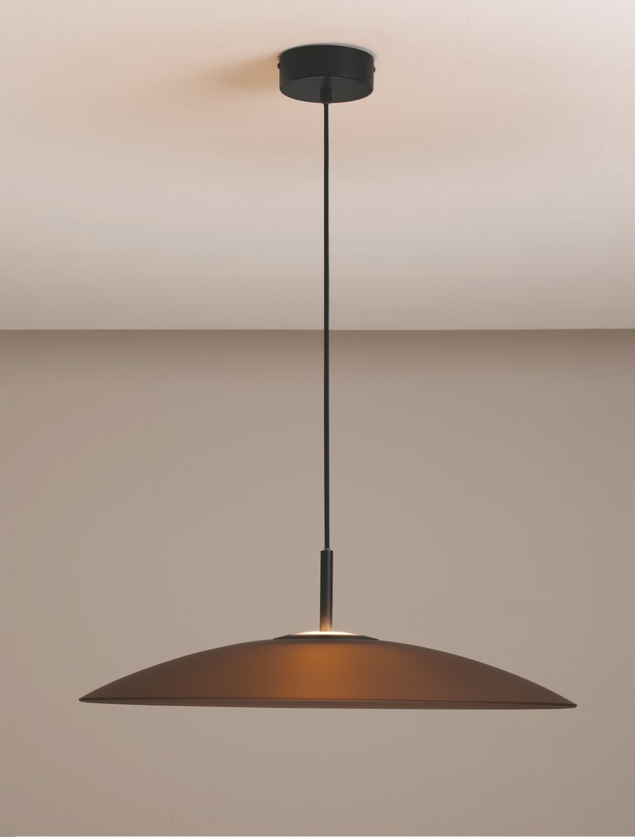 Lampa wisząca Peca z jedną żarówką LED 17W, o czarnej metalowej podstawie i brązowym kloszu w kształcie stożka. Zawieszona na cienkim, czarnym przewodzie, idealna do nowoczesnych wnętrz. Tło w odcieniu jasnobeżowym.