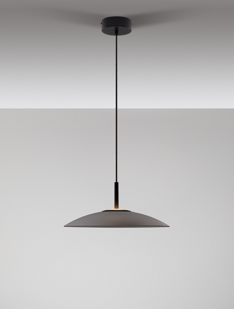Lampa wisząca Peca w kolorze czarnym z szarym kloszem, zawieszona na cienkim przewodzie. Klosz ma kształt stożka z lekko zaokrąglonym końcem. Elementy metalowe i minimalistyczny design. Idealna do nowoczesnych wnętrz.