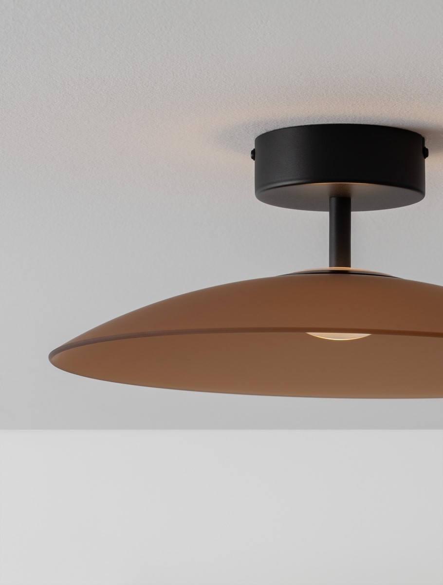 Lampa sufitowa Peca z jednym źródłem LED 12W, czarna z brązowym kloszem. Ujęcie z dołu, pokazujące okrągły, płaski kształt klosza, zamontowana na czarnej podsufitce. Tło jasne, jednolite.