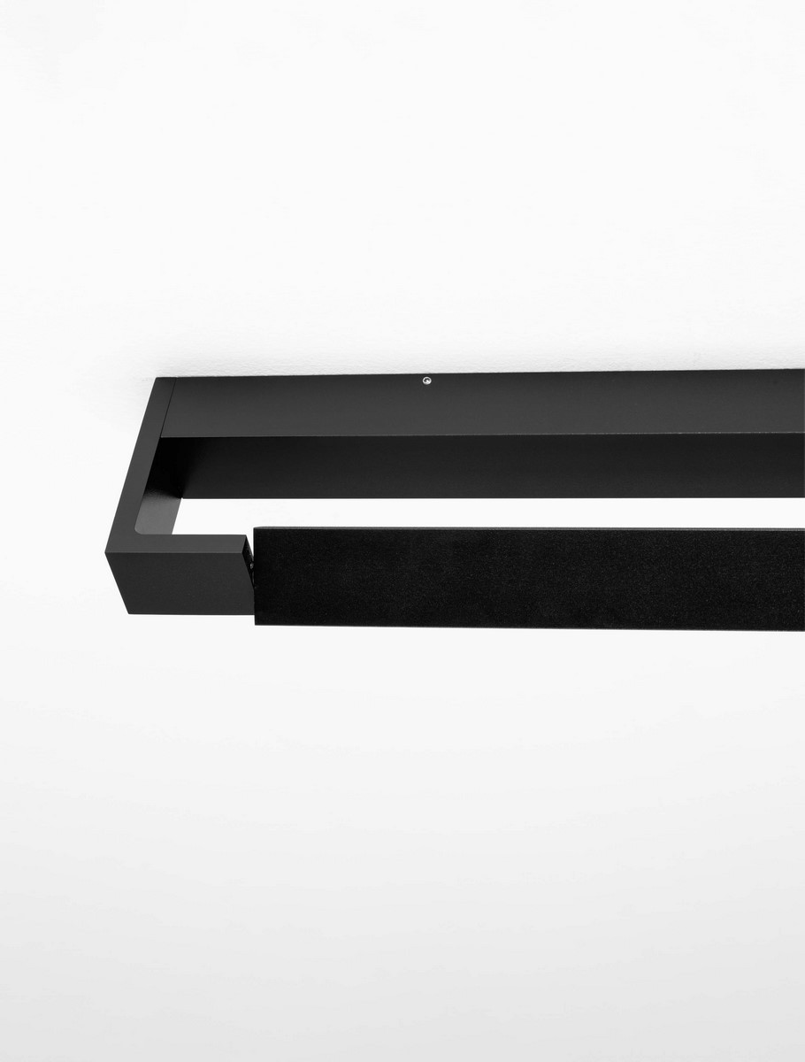 Kinkiet Justo 1xLED 12W w kolorze czarnym, o prostokątnym kształcie, z matowym wykończeniem. Ujęcie z boku, montowany na ścianie, z widocznym otworem do mocowania. Na tle białej ściany, bez dodatkowych detali.